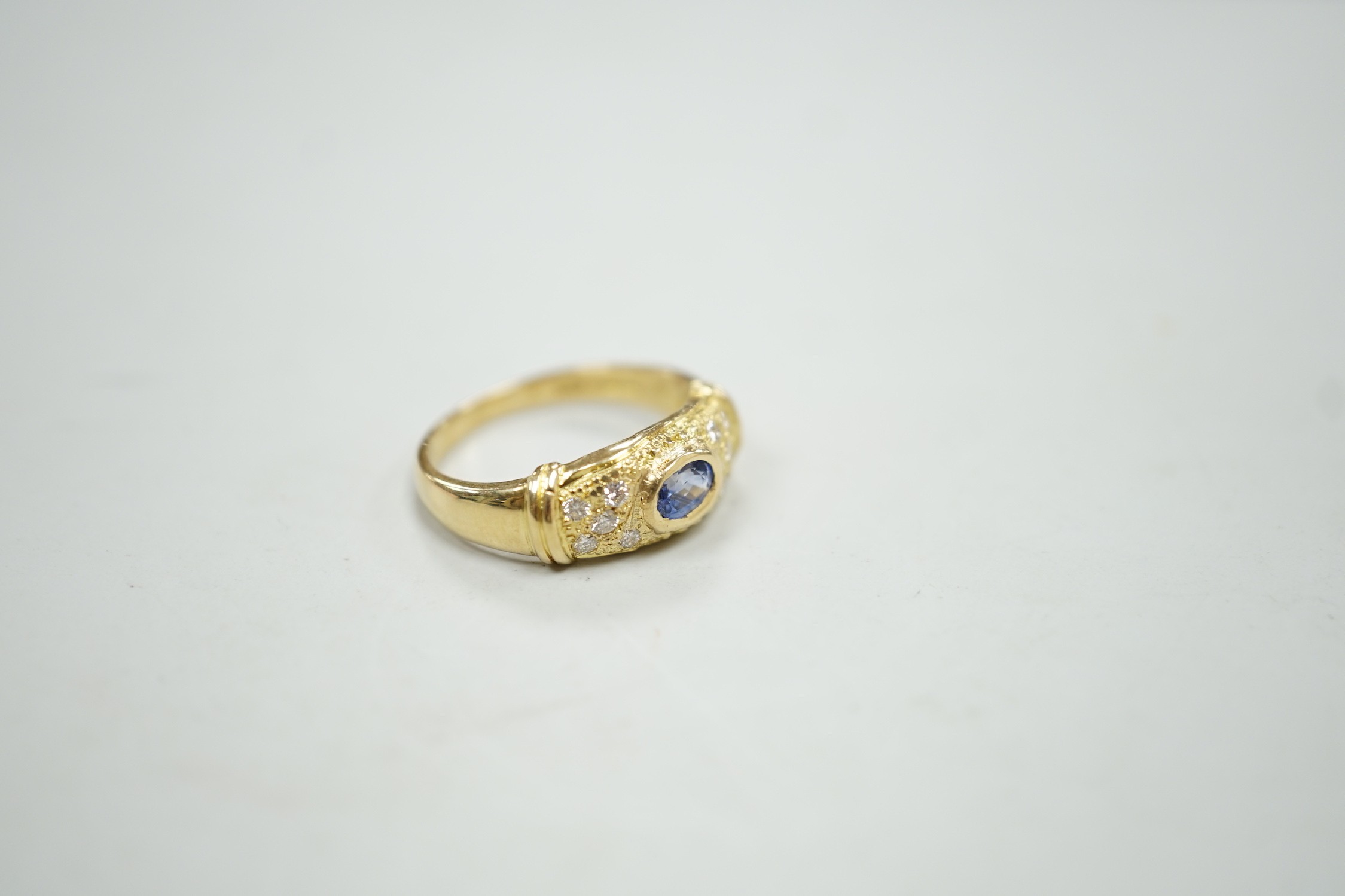 A modern 18ct gold, single stone oval cut sapphire and ten stone diamond chip set ring, size N/O, gross weight, 5.3 grams.